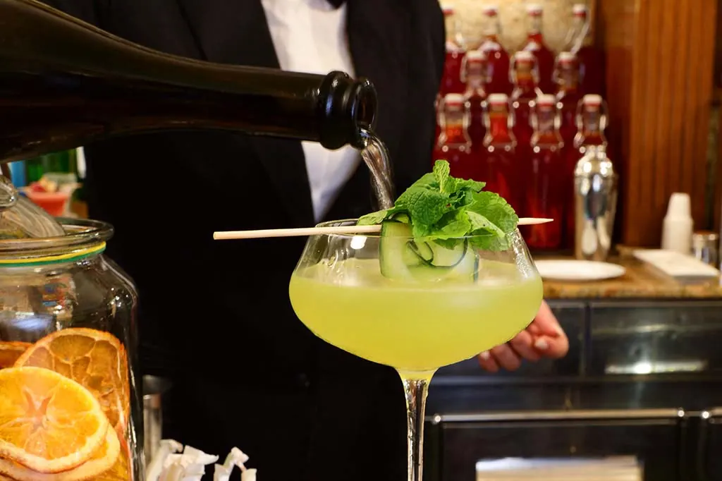 Il barman di Ceraldi Caffè versa lo spumante in un cocktail con menta e cetriolo